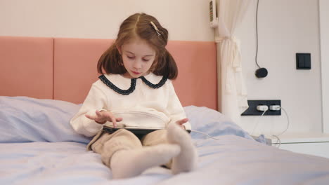 young girl using a tablet on her bed.