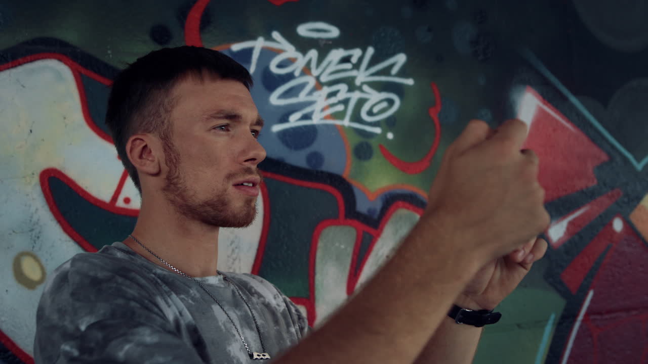 Adolescente concentrato che scatta una foto con il cellulare allo skate park con graffiti.