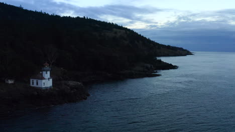 lighthouse drone. drone flying toward lighthouse over water at sunset in the pacific north west san juan islands. birds flying over ocean with forest in background. lighthouse 4k