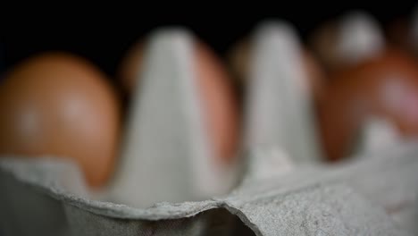 blurredly seen and then a hand seen placing tree eggs in the tray, eggs in a paper tray, food and cooking