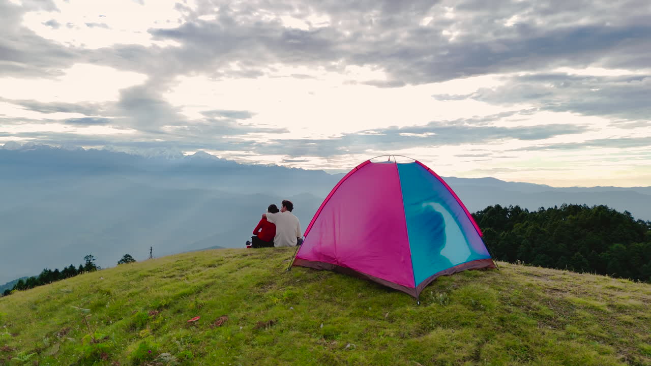 드론 촬영은 네팔 도라카의 세일룬 언덕에 있는 캠핑 텐트에서 포옹하는 로맨틱 한 커플을 포착합니다.