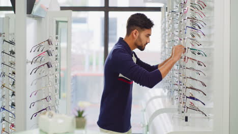 joven intentando ponerse gafas en una optometría