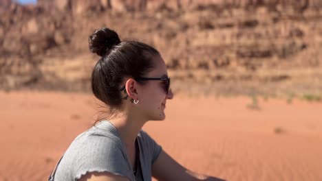 mujeres con gafas de sol sonriendo en el desierto rojo de wadi rum en jordania mientras están en la parte trasera del jeep