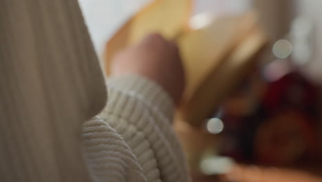 close up of lady hand flipping page of open book in soft daylight near window, cozy setting includes blurred mug on wooden table and lush green plant in background