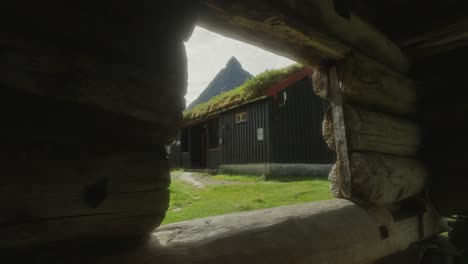 A-young-couple-hiking-through-a-rustic-village-in-Innerdalen,-Norway,-with-mountain-views,-midday