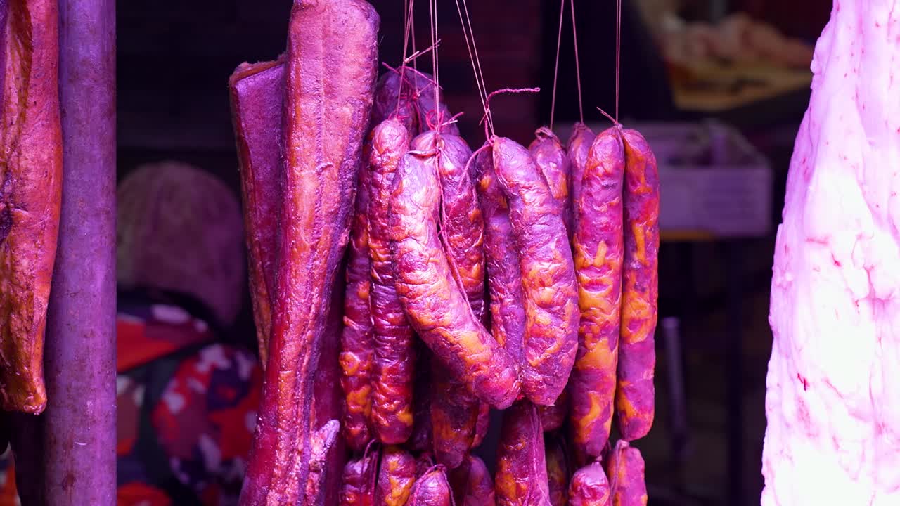 Slow-motion shot of traditional spicy sausages hanging in a vibrant Chongqing market. China