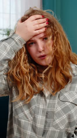 woman sits on sofa making facepalm gesture feeling disappointed frustrated after unexpected failure