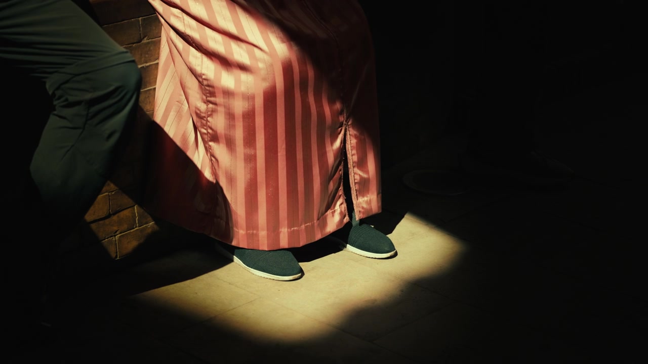 Person Wearing Striped Robe Standing in Dramatic Spotlight
