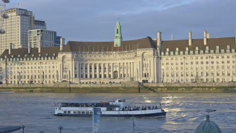 boat sailing along river thames with county hall in background, london