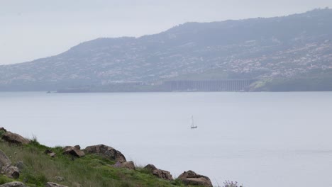 Sailing-yacht-navigate-along-Madeira-coast-and-runway-platform-of-airport