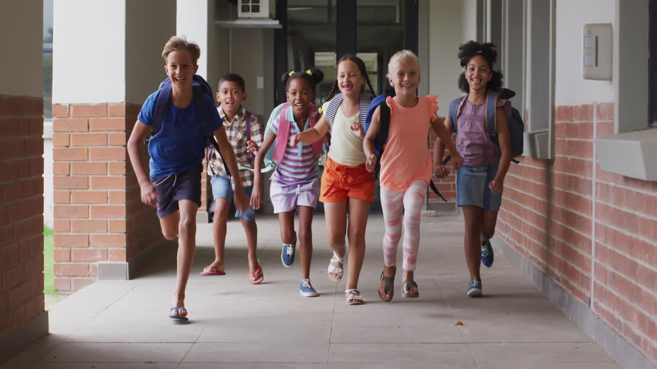 Video of happy diverse pupils running on school corridor