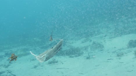 Eine-Weggeworfene-Medizinische-Maske-Aus-Dem-Covid-19-Ausbruch-Findet-Ihren-Weg-In-Den-Ozean,-Der-Als-Meeresmüll-Und-Trümmer-Herumschwimmt