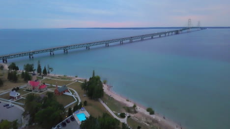 cinematic aerial drone mackinaw bridge lighthouse michigan sunset dusk purple pink stunning great lakes landscape mid summer up north petoskey harbor springs peaceful cars cross bridge forward motion