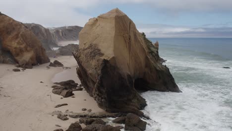 Aerial-orbiting-Rock-formation-Called-Penedo-do-guincho-on-Santa-Cruz-Beach,-Portugal