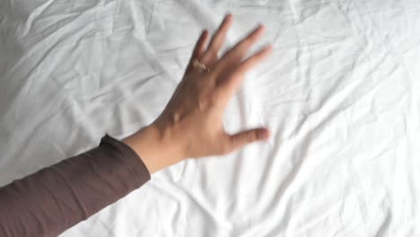 hand touching white bed sheets