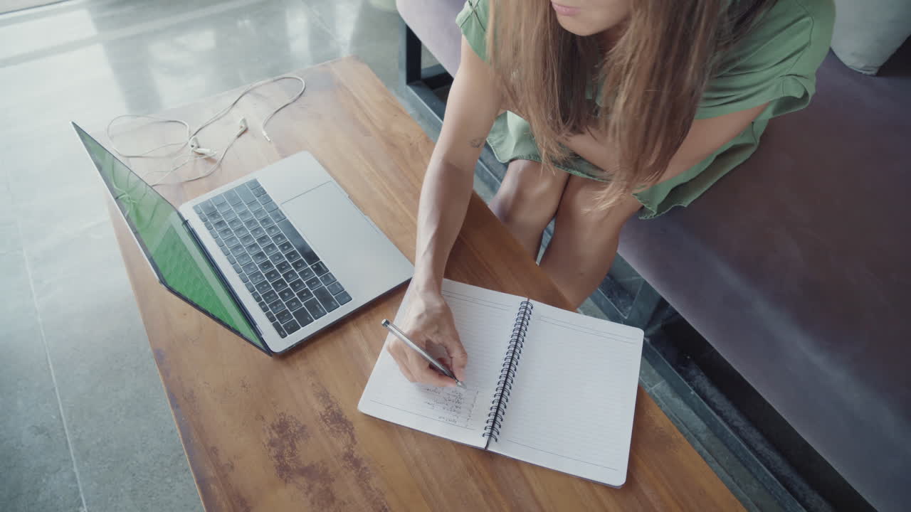 Young Woman Writing List on Notebook