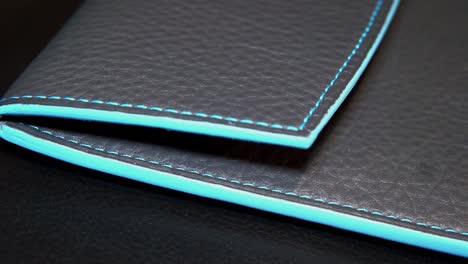 closeup-shot-of-a-black-leather-purse-with-blue-edges