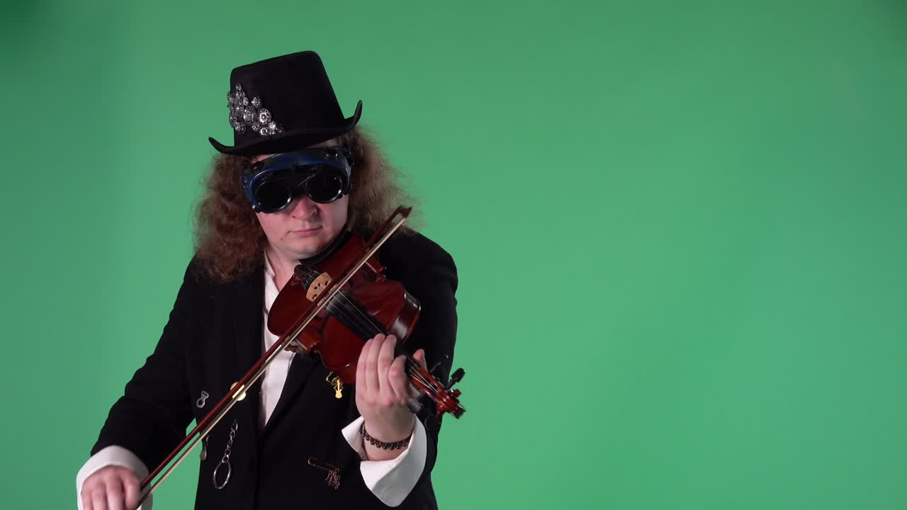 un violinista con un traje negro, sombrero y gafas originales toca el violín con maestría. el hombre toca las cuerdas con un arco para crear una melodía. pantalla verde tecla de croma. cámara lenta.