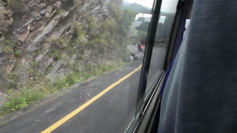 pov bus ride through nepal's rugged interior. camera facing out of the side window. motorcycle is driving in front