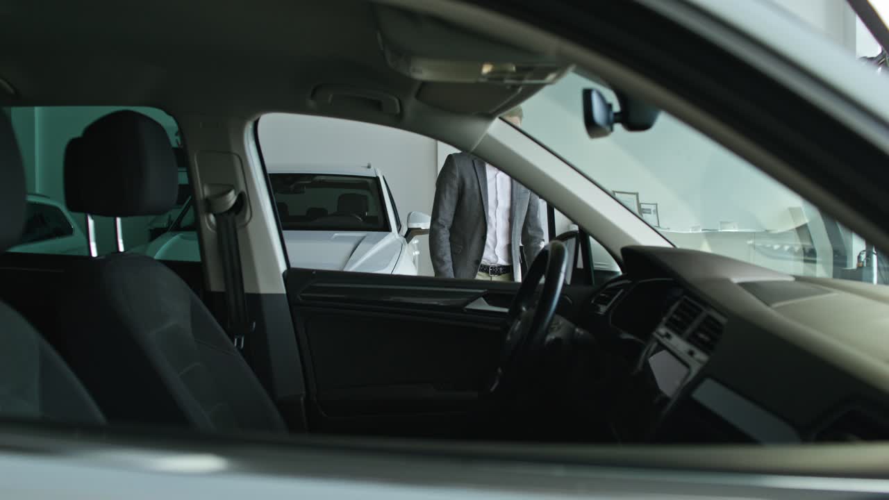 hombre dentro de un coche en una sala de exposiciones