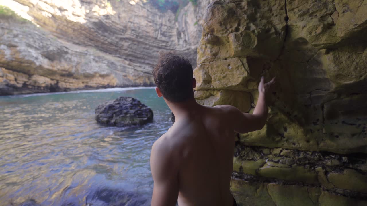 un joven deportivo caminando por la cueva costera.