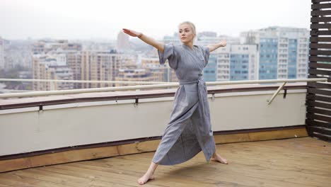 yoga couch in robe at terrace doing warrior pose virabhadrasana, triangle pose utthita trikonasana