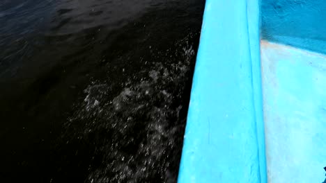 detail shot of the side of a blue fiber motorboat navigating as waves splash