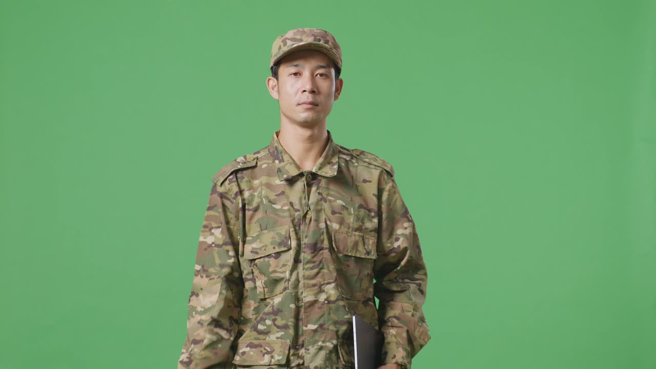 녹색 스크린 배경 스튜디오에서 는 동안 태블릿을 들고 있는 아시아인 군인