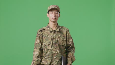 asian man soldier holding a tablet while walking in the green screen background studio