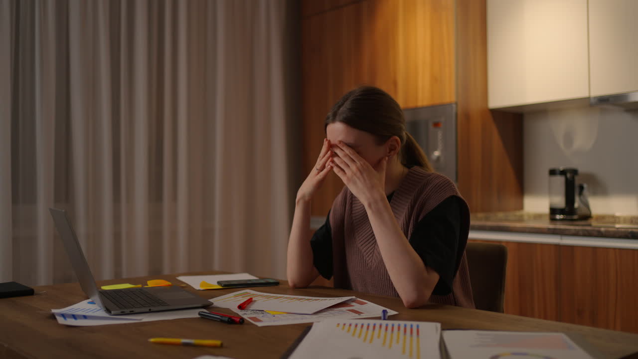 Side view A woman works remotely in a home office at a desk with a laptop and notes data on a graph a business economist analyst. Writes down makes notes
