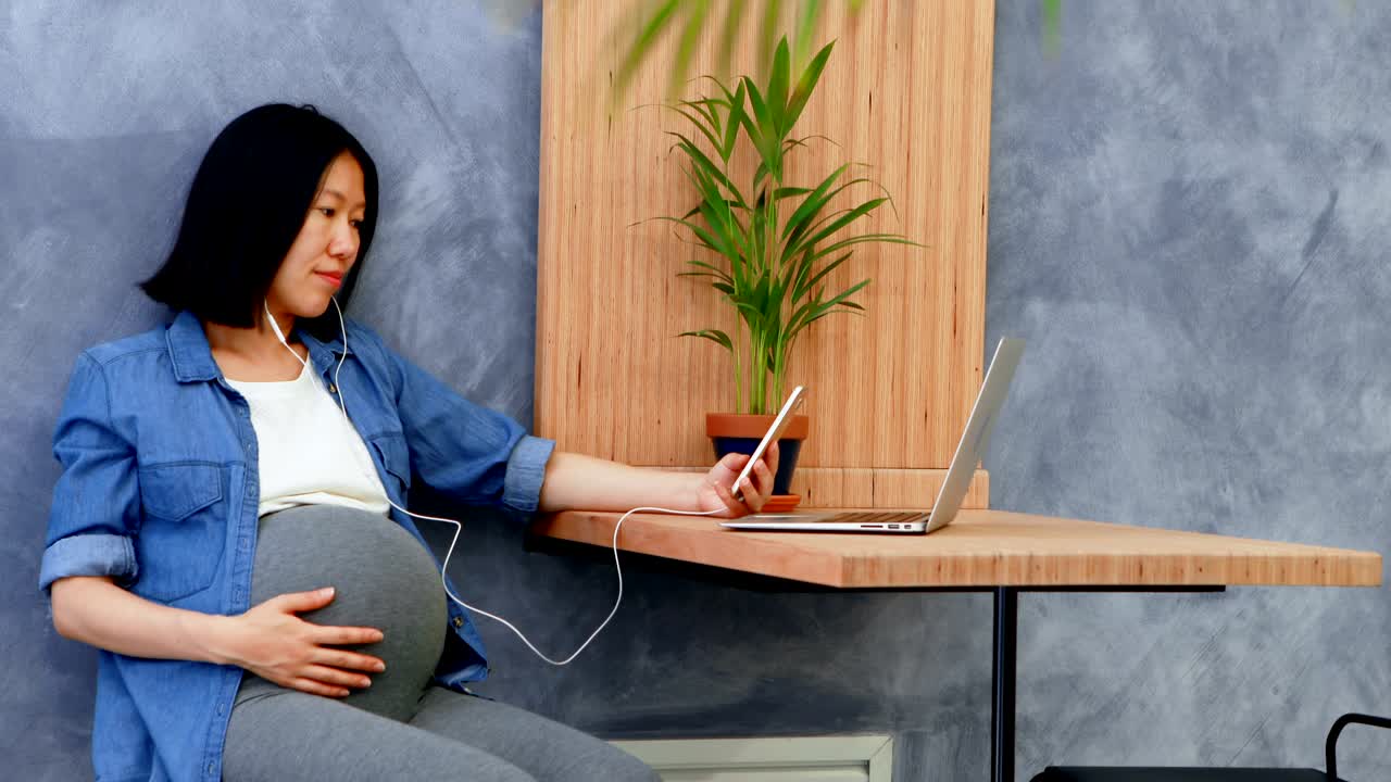 임신 한 여성이 휴대 전화 4k에서 음악을 듣고 있습니다.