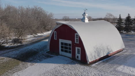 snow covered red farm barn in the rural countryside, aerial