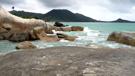 ocean waves crash on the rocks on the mountain backdrop