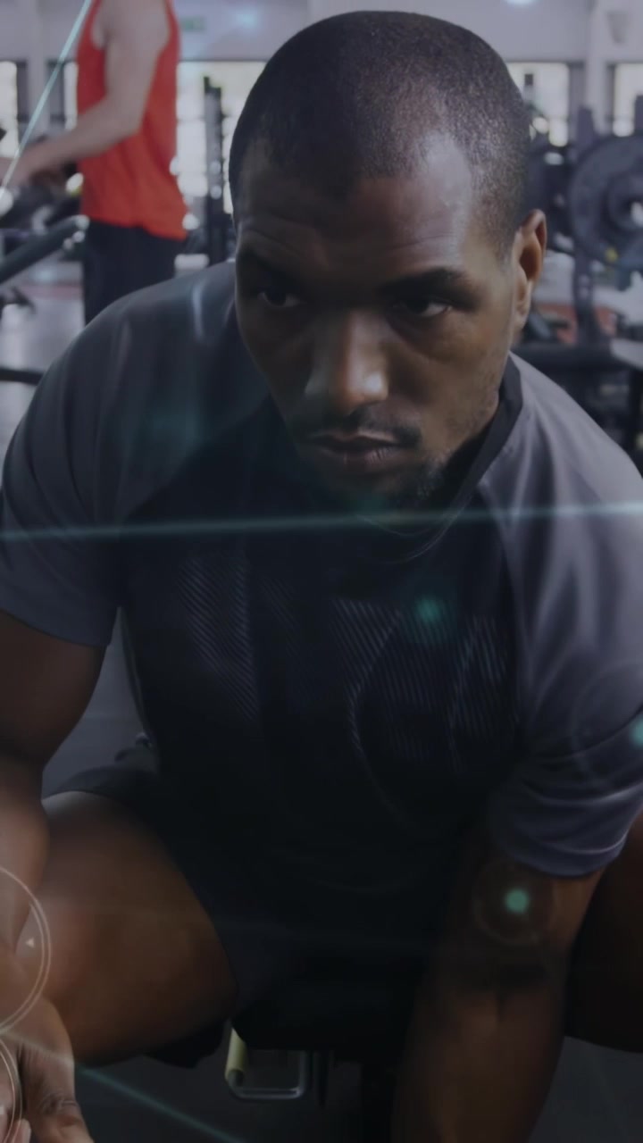 Vertical video: Man gripping dumbbell starting curl on bench, graphics tracking biceps for fitness