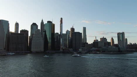 Vista-Aérea-De-Gran-Angular-Del-Bajo-Manhattan,-Ciudad-De-Nueva-York-Con-Barcos-En-El-Río-Este-Al-Atardecer-En-Una-Clara-Tarde-De-Verano