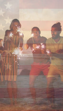 animation of flag of united states of america over happy diverse friends with sparklers on beach