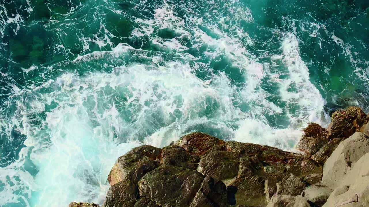 Vagues de l’océan émeraude se brisant sur le rivage rocheux volcanique