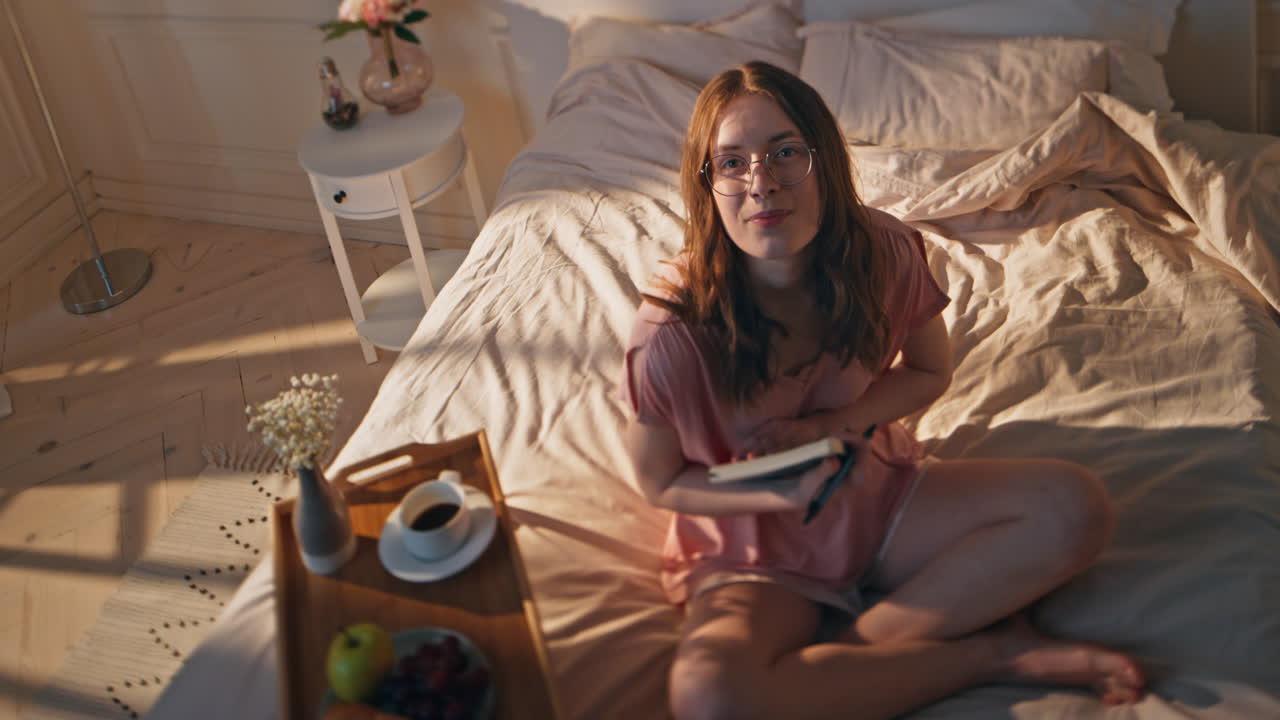 estudiante sonriente sosteniendo el diario por la mañana. mujer soñadora disfrutando del tiempo libre en casa
