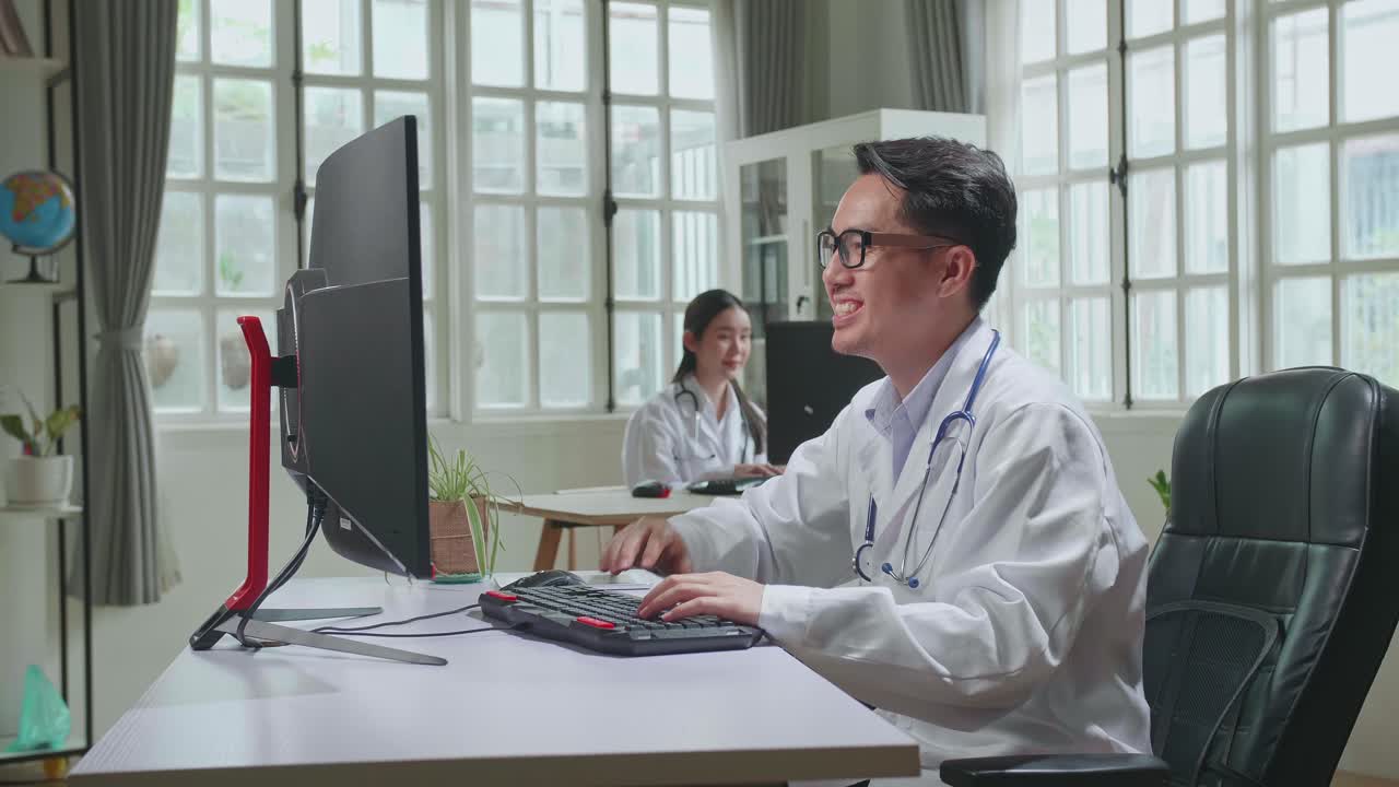 Asian Male Doctor Communicates With Patient By Video Link, Doctor Consults Patient Using Modern Technologies, Using Desktop Computer In Workplace