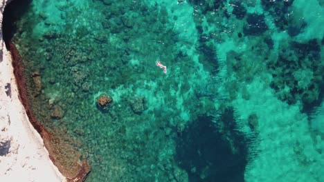 birds eye view of people swimming in crystal clear blue and turquoise water - 4k footage