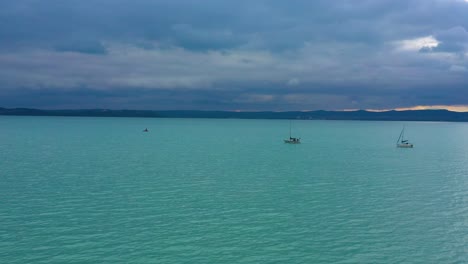 Zwei-Boote-Segeln-Auf-Dem-Plattensee-Im-Sonnenuntergang-Mit-Wolken-Bei-Regenwetter,-Drohnenaufnahmen