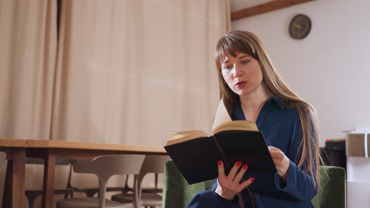Counselor with long hair and focused expression reads from notebook while seated in quiet room filled with soft natural light and wooden furniture, reflecting calm and thoughtful professional environment
