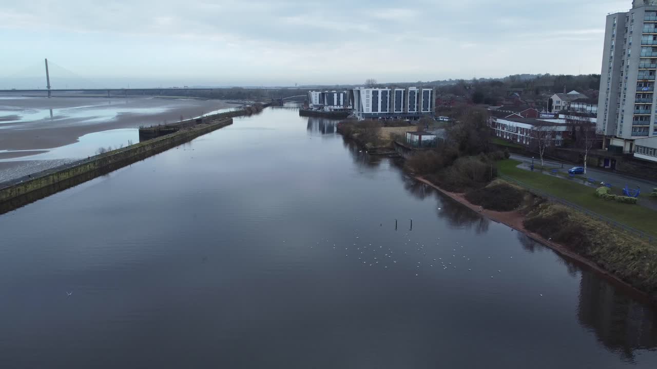 Luftfoto af en gammel britisk by under byfornyelse med lejlighedsblokke langs en vandvej, zoom ud.