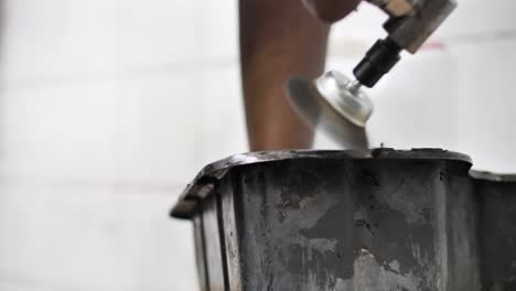 cleaning car part with a wire brush on a rotary tool, garage, mechanic workshop