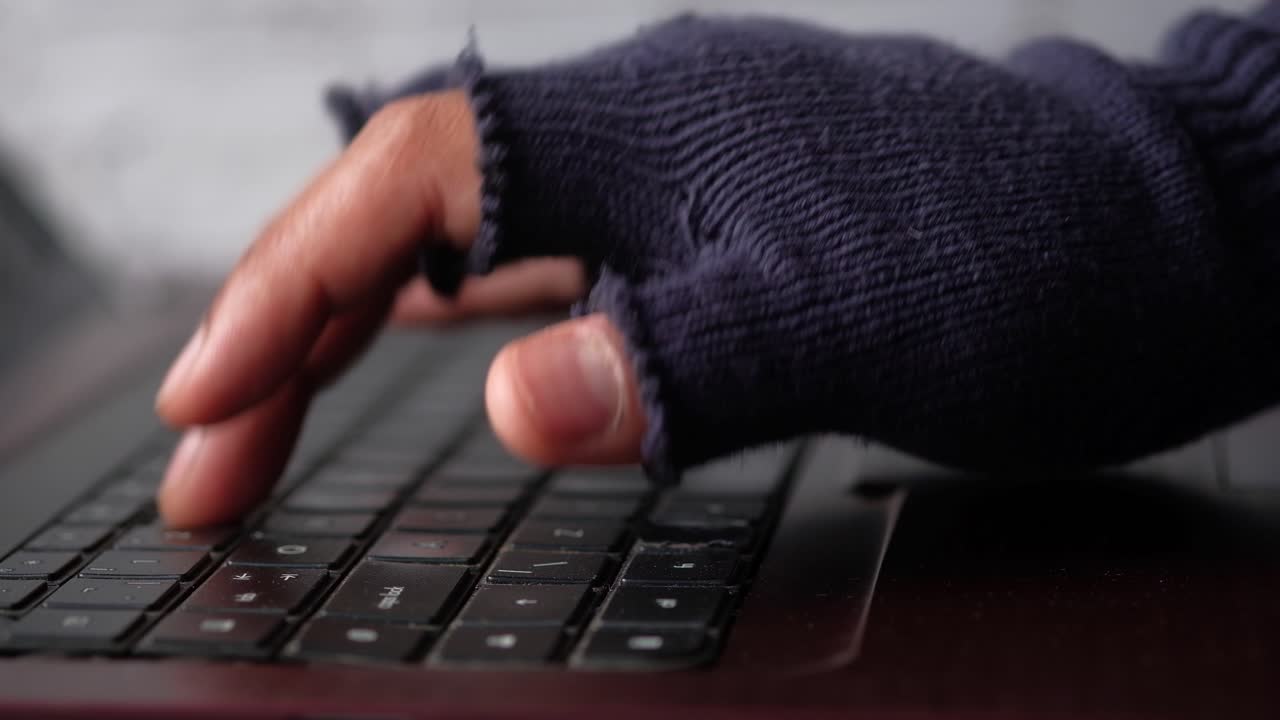 Hands with gloves typing on a laptop keyboard