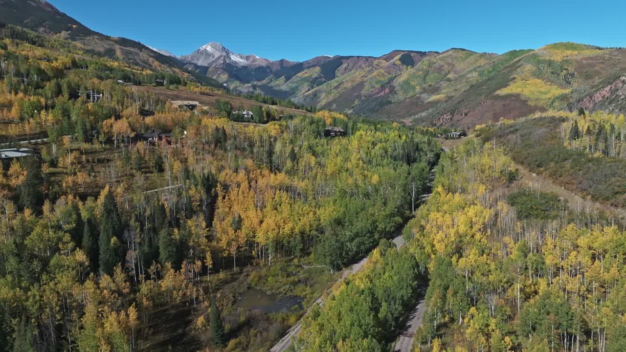 Fall colors cover the mountains and roads of Snowmass Village, Aspen, seen from above by drone