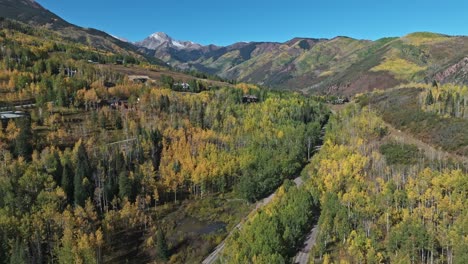 fall colors cover the mountains and roads of snowmass village, aspen, seen from above by drone