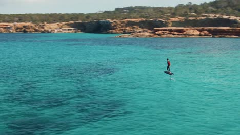 aerial view of a surfer surfing in the blue water of cala escondida, spain