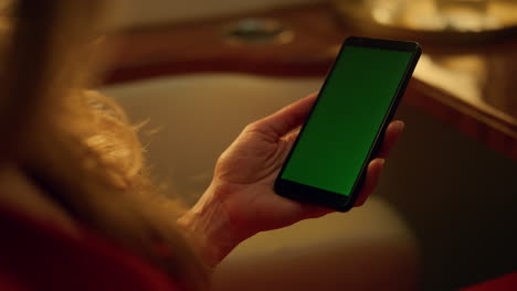 Closeup-hand-hold-green-screen-phone.-Middle-aged-woman-using-mockup-device