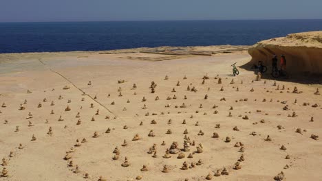 Manmade-rock-formations-in-spiral-shape-on-the-coast-near-salt-pans,-Malta,-Aerial-low-level-fly-over-shot